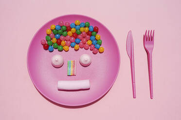 Studio shot of plastic plate with colorful candies and anthropomorphic face made of marshmallows and gum drop - GEMF04060