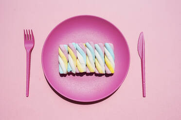 Studio shot of plastic plate with row of twisted marshmallows - GEMF04064