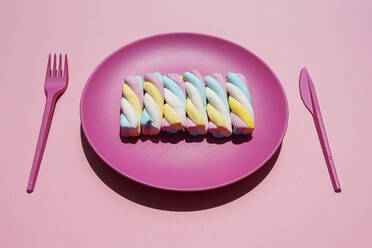 Studio shot of plastic plate with row of twisted marshmallows - GEMF04065