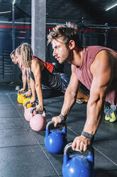 Seitenansicht eines athletischen, starken Mannes beim Training mit Gewichten im Fitnessstudio - ADSF11151