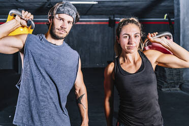 Muscular fellows with kettle bells looking at camera in contemporary health club - ADSF11154