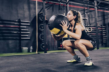 Von unten sportliche Frau in Sportkleidung beim Training mit Fitball im Fitnessstudio - ADSF11164