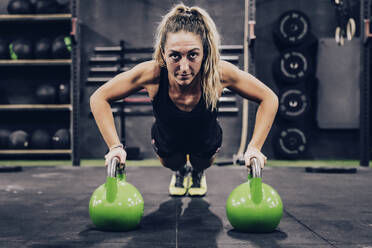 Muskulöse Frau auf Hände in Hanteln in modernen Fitness-Studio auf unscharfen Hintergrund - ADSF11169