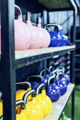 Set of colorful kettlebells on shelves in modern health club - ADSF11170