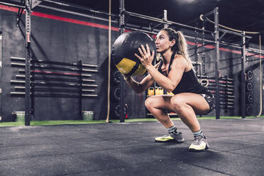 Sportliche Frau in Sportkleidung beim Training mit Fitball im Fitnessstudio - ADSF11182