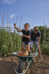 Vater und Tochter haben Spaß mit der Schubkarre im Garten - VEGF02688