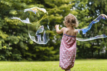 Mädchen spielt mit Seifenblasen im Park - DIGF12910