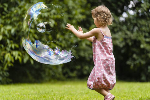 Cute girl exploding bubble at public park - DIGF12914