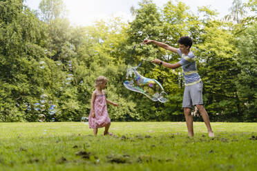 Bruder macht Seifenblase für Schwester im Park - DIGF12923