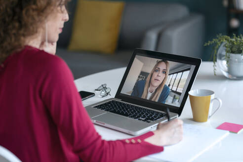 Junge Unternehmerin nimmt an einer Videokonferenz über einen Laptop im Home Office teil - JSRF01070