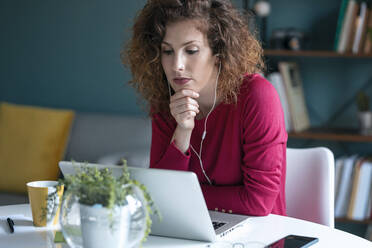 Geschäftsfrau bei einer Videokonferenz mit Blick auf den Laptop bei der Arbeit von zu Hause aus - JSRF01073