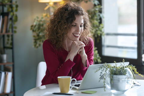 Happy businesswoman using laptop while working from home stock photo