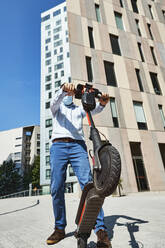 Entrepreneur holding electric push scooter in city during sunny day - VEGF02751