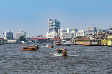 Thailand, Bangkok, Ferries on Chao Phraya river with city skyline in background - RUNF04066