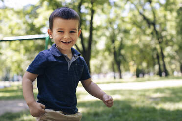 Smiling cute boy playing in ground during summer - MOMF00890