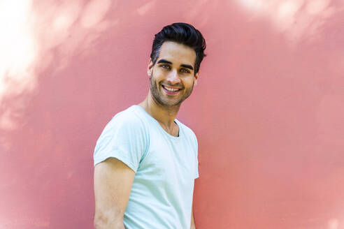 Smiling man standing against pink wall - AFVF06903