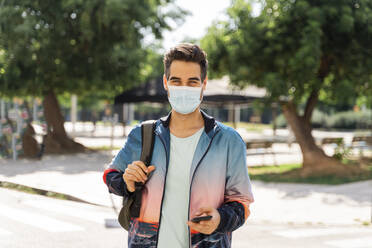 Man wearing face mask standing in city during COVID-19 - AFVF06911