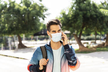 Man wearing face mask talking on phone in city during COVID-19 - AFVF06913