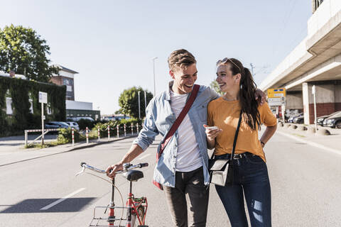 Happy young couple walking on street in city stock photo