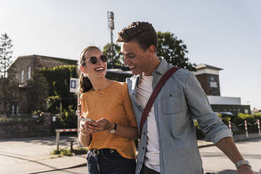 Happy boyfriend and girlfriend walking on street in city - UUF20872