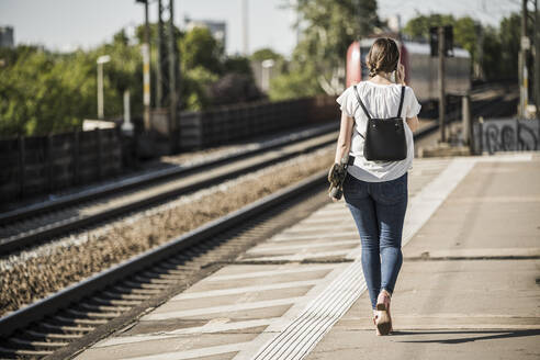 Frau mit Skateboard auf dem Bahnsteig eines Bahnhofs - UUF20891