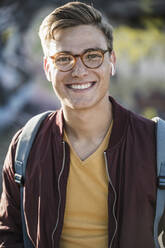 Lächelnder gut aussehender junger Mann mit Brille - UUF20919