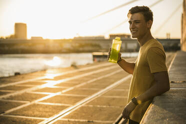 Mann mit Wasserflasche nach dem Training bei klarem Himmel - UUF20970