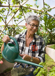 Ältere Frau bei der Gartenarbeit in geodätischer Kuppel - MINF15088