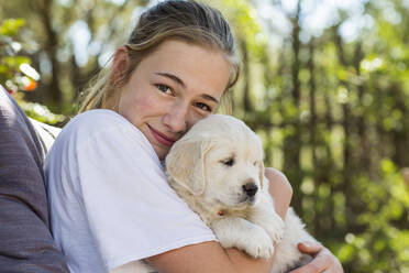 Teenager-Mädchen hält einen englischen Golden Retriever Welpen - MINF15133