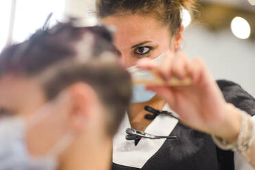 Friseurin bei der Arbeit mit Gesichtsmaske beim Styling eines jungen Mädchens - CAVF88360