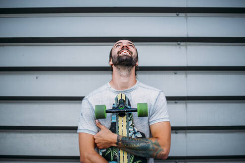 Junge posiert mit Skateboard in der Hand - CAVF88377