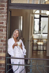 Glückliche Frau trinkt Tee auf dem Balkon - MCF01106