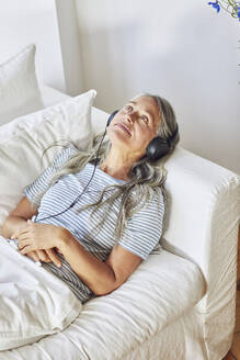 Nachdenkliche Frau beim Musikhören im Wohnzimmer - MCF01135