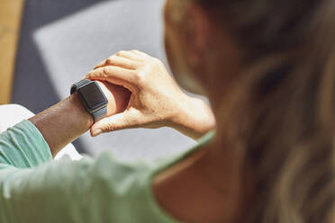 Woman checking the time in living room - MCF01181