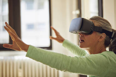 Woman using VR glasses at home - MCF01190