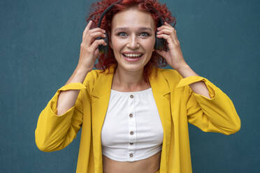 Junge Frau mit roten lockigen Haaren, die Kopfhörer trägt und Spaß am Musikhören hat - VPIF02799