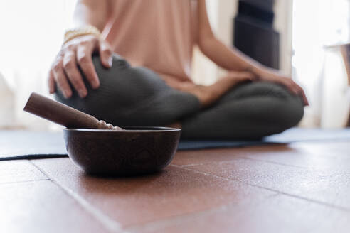 Woman doing yoga at home, singing bowl in the foreground - FMOF01040