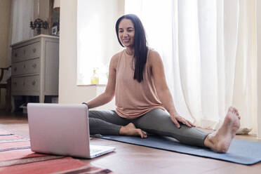 Smiling mature woman in front of laptop at home - FMOF01046