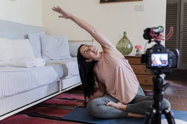 Smiling mature woman during yoga excersice in front of digital camera - FMOF01056