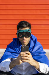 Geschäftsmann mit Smartphone, Superheldenumhang und VR-Brille - AFVF06935