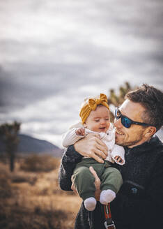 Ein Mann mit einem Baby steht in der Wüste von Kalifornien - CAVF88396