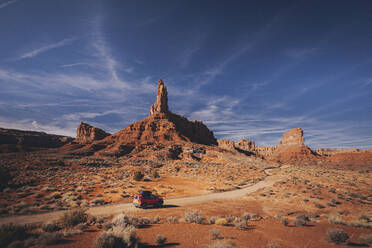 Ein orangefarbenes Auto fährt durch das Valley of Gods, Utah - CAVF88436