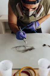 Nahaufnahme eines Airbrush-Malers mit Maske, der ein Auge auf ein Papier zeichnet. - CAVF88459