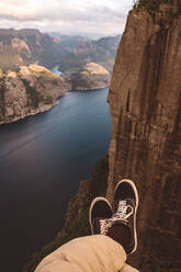 Person cross legged at edge of cliff with a fjords view in Norway - CAVF88467