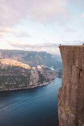 Mann sitzt am Rande einer Klippe am Preikestolen, Norwegen - CAVF88469