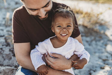Close up of father holding young toddler girl at beach - CAVF88473