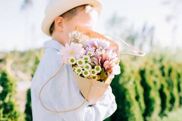 Junger Junge hält einen schönen Blumenstrauß im Sommer - CAVF88509