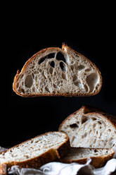 Stücke von leckeren frischen Brot fallen auf Serviette auf dem Tisch vor schwarzem Hintergrund - ADSF11566