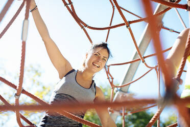Woman rope climbing in park - CUF56217
