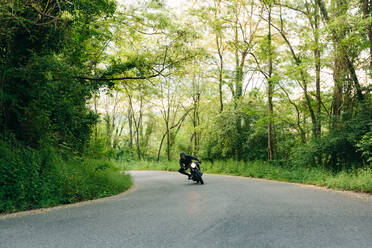 Junger männlicher Motorradfahrer auf Oldtimer-Motorrad in einer Kurve auf einer Landstraße, Florenz, Toskana, Italien - CUF56226